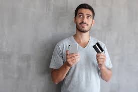 Hombre decidiendo si pagar con tarjeta de debito o crédito